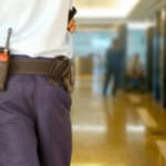 vigilante di spalle che che cammina con una radiotrasmittente sulla cintura