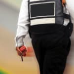 vigilante di spalle che che cammina con una radiotrasmittente in mano