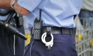 dettaglio cintura vigilante in divisa con manette e radiotrasmittente